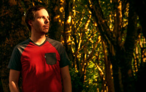 Slowtide - A Gentle Reminder - Promo Picture. Kevin Werdelmann in a forest during sunset.